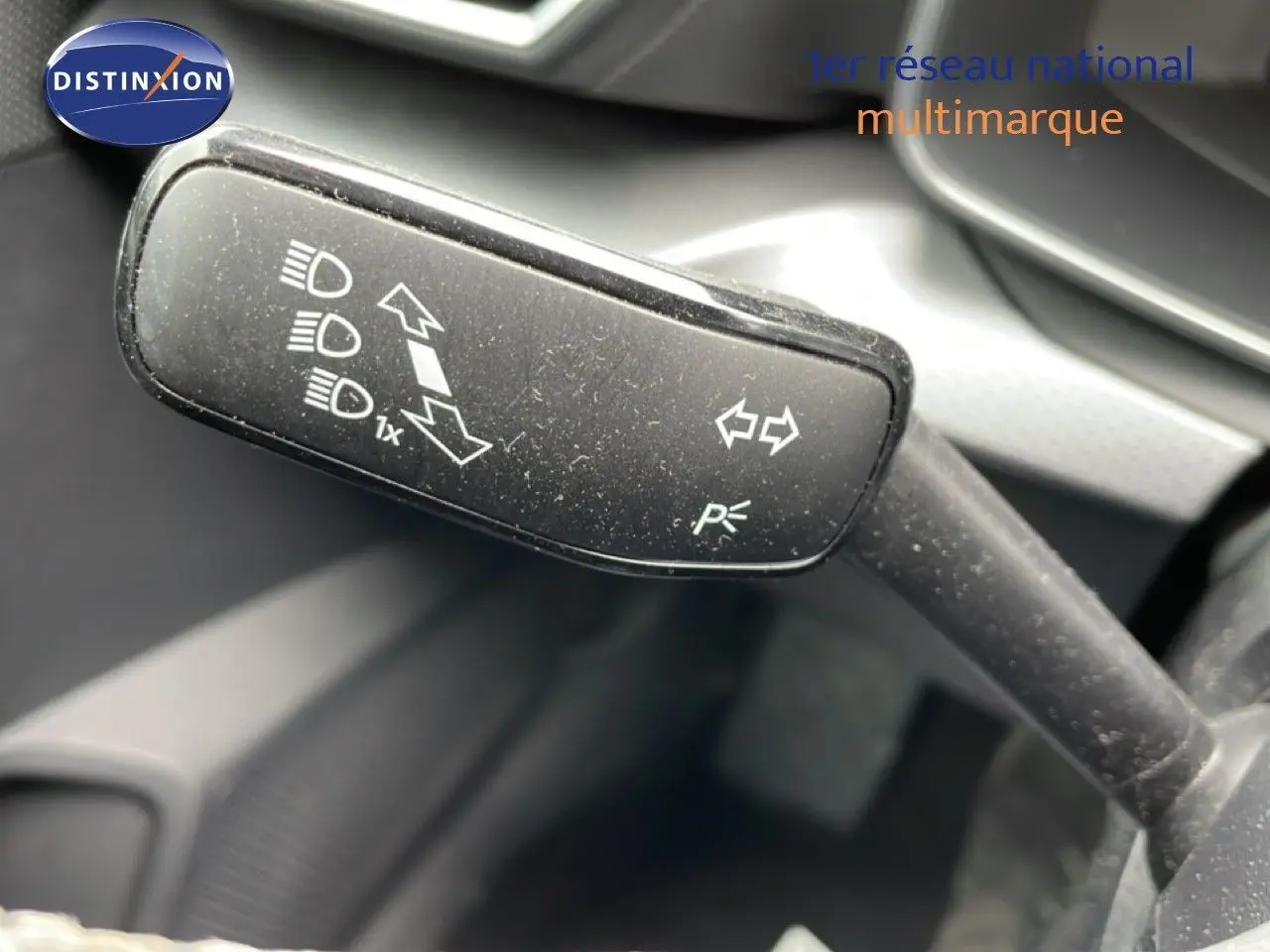 Gros plan sur la commande de clignotants et feux du SEAT LEON ST gris magnétique, intérieur noir visible en arrière-plan.
