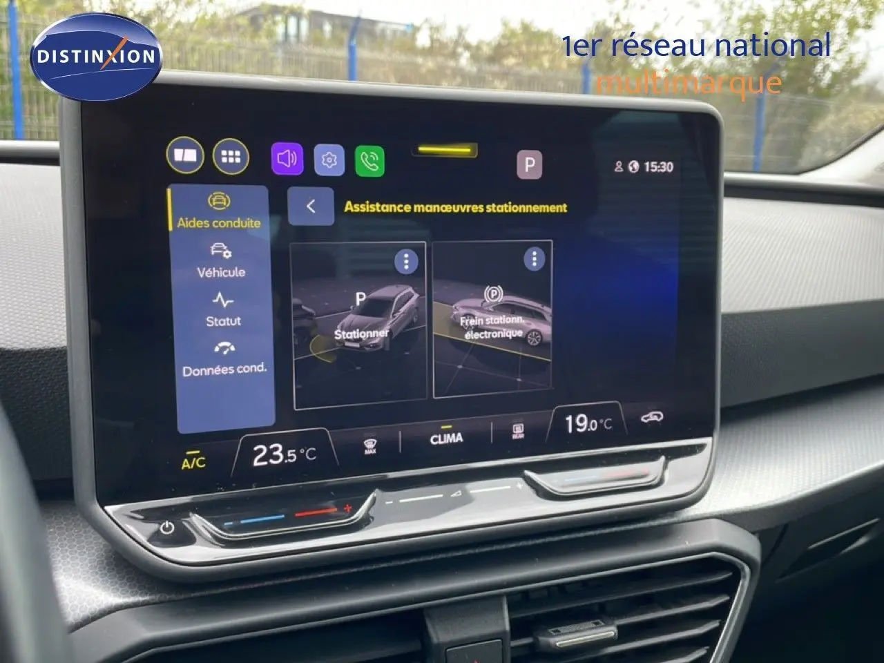 Vue rapprochée de l’écran tactile central du SEAT LEON ST gris magnétique, affichant l’assistance au stationnement.