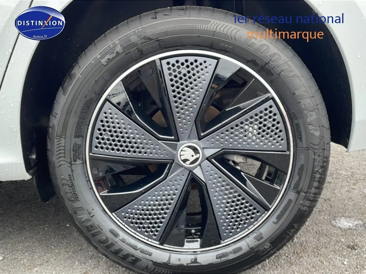 Gros plan sur la jante noire et grise du Skoda Kamiq blanc nacré, mettant en valeur son design moderne perforé.