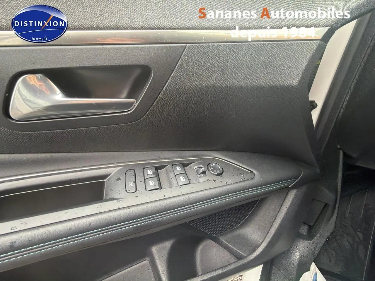 Gros plan sur la porte avant gauche noire du Peugeot 3008 Hybrid 2021 avec commandes des vitres et poignée chrome.
