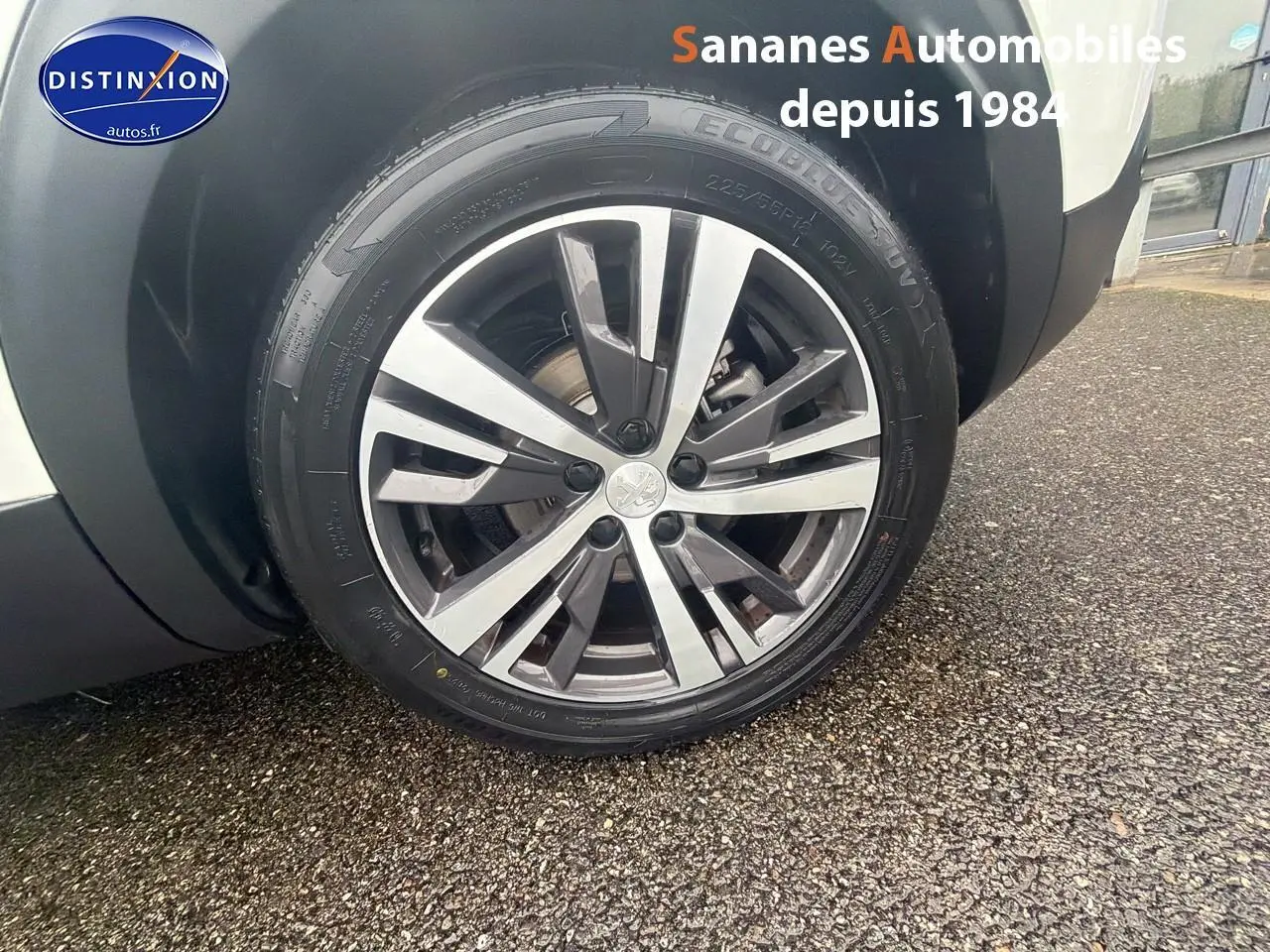 Gros plan sur la jante alliage avant droite du Peugeot 3008 Hybrid blanc, avec logo Peugeot au centre.