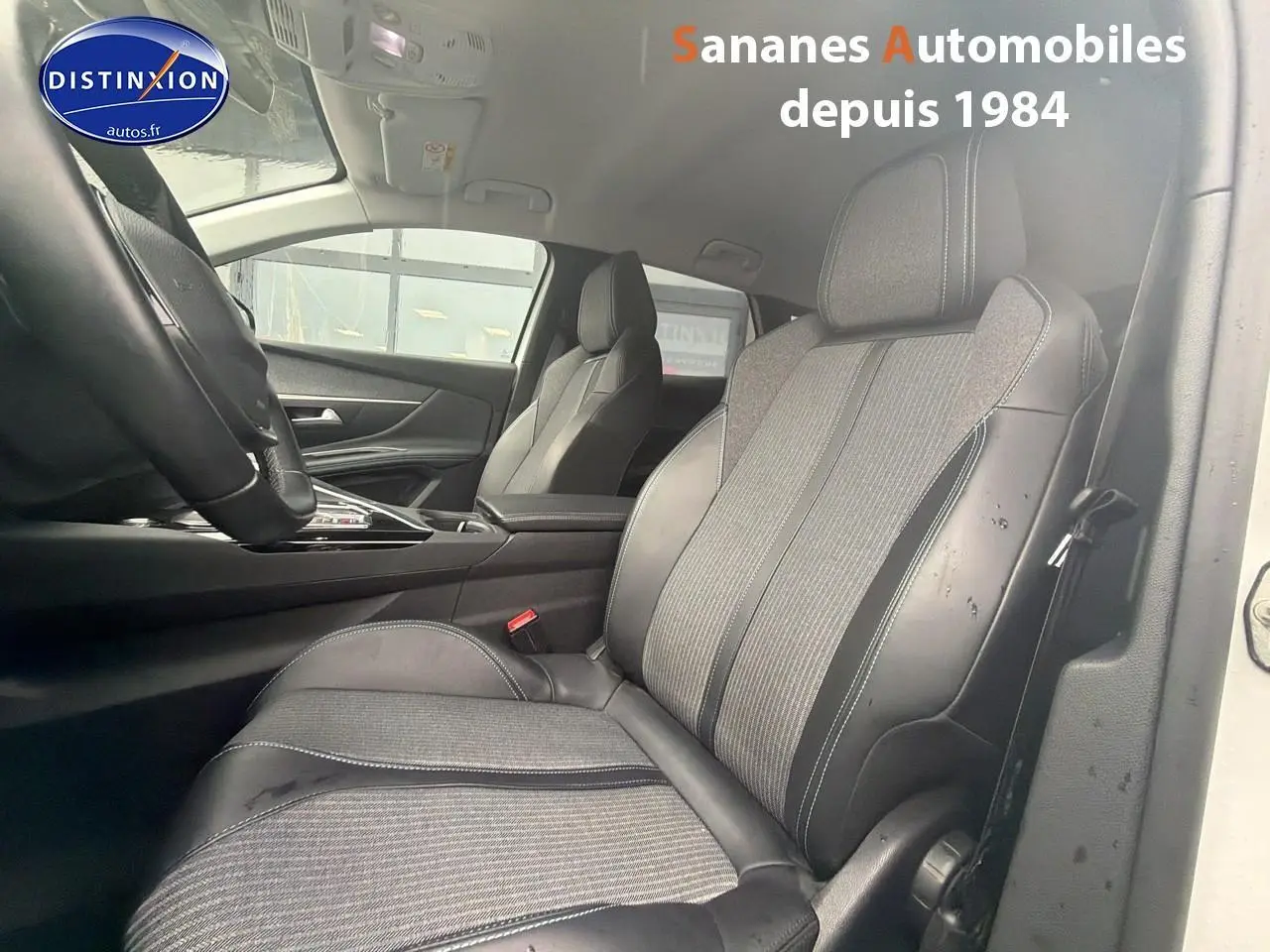Vue intérieure côté conducteur du Peugeot 3008 Hybrid 225 blanc, mettant en valeur les sièges en cuir et tissu gris.