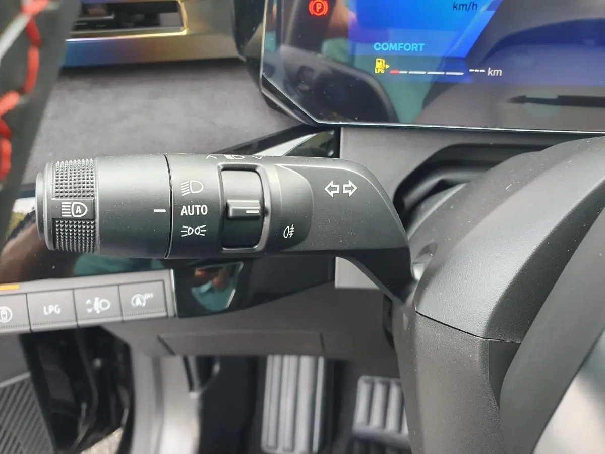 Gros plan sur la commande des feux et clignotants à gauche du volant dans le tableau de bord numérique de la Renault Clio VI noire étoile.