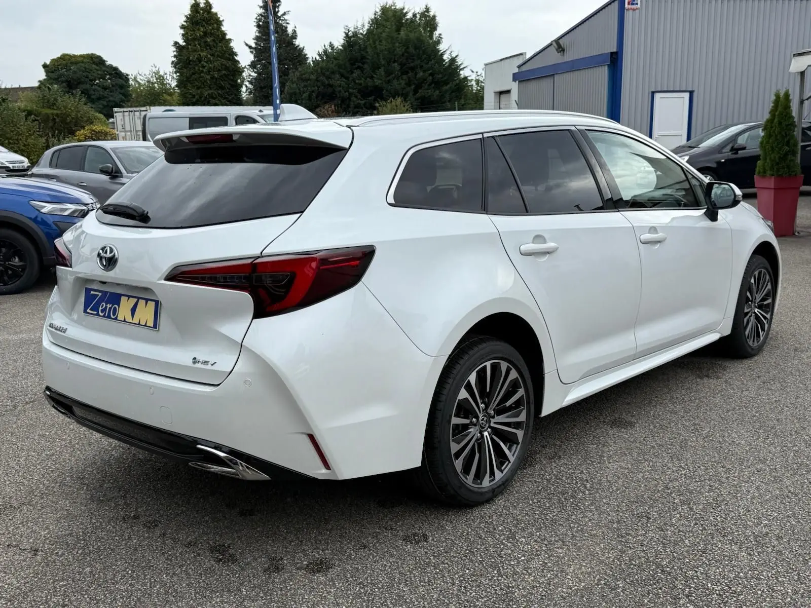 Toyota Corolla Touring Sport blanche nacrée vue de trois quarts arrière droit, avec jantes alliage et feux arrière LED distinctifs.