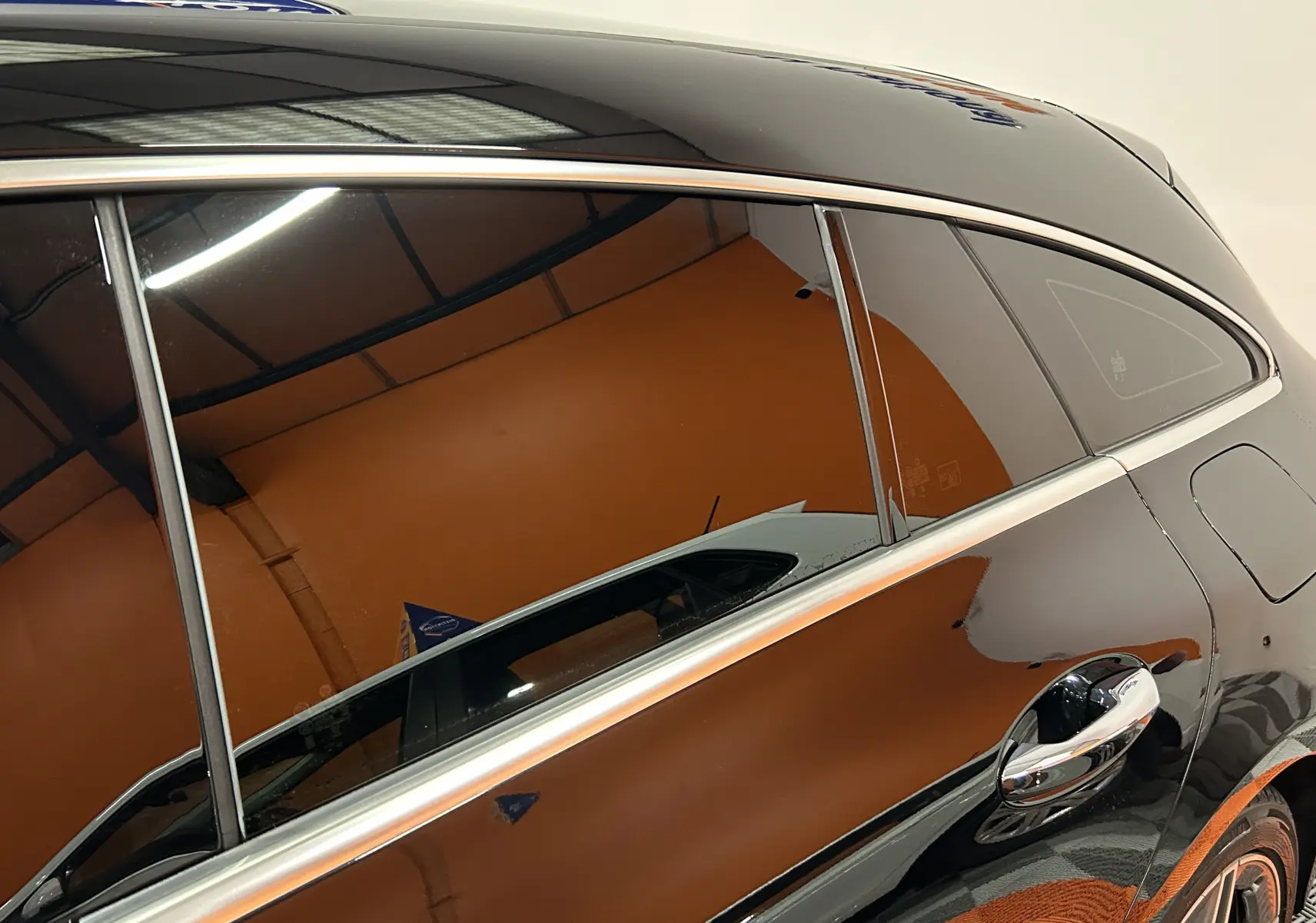 Vue latérale droite rapprochée d'une Mercedes Classe CLA Shooting Brake II 200D AMG noir métallisé avec poignées chromées.