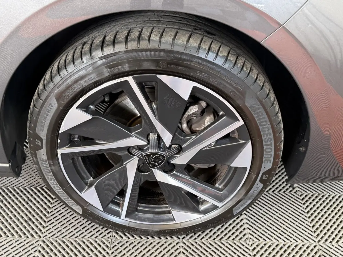 Gros plan sur la roue avant droite de la Peugeot 308 gris foncé, avec jante alliage au design moderne bicolore.