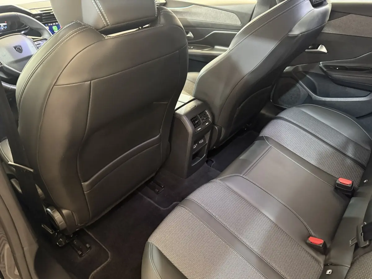 Vue intérieure arrière de la Peugeot 308 gris foncé, montrant les sièges en cuir et tissu et la console centrale avec aérateurs.