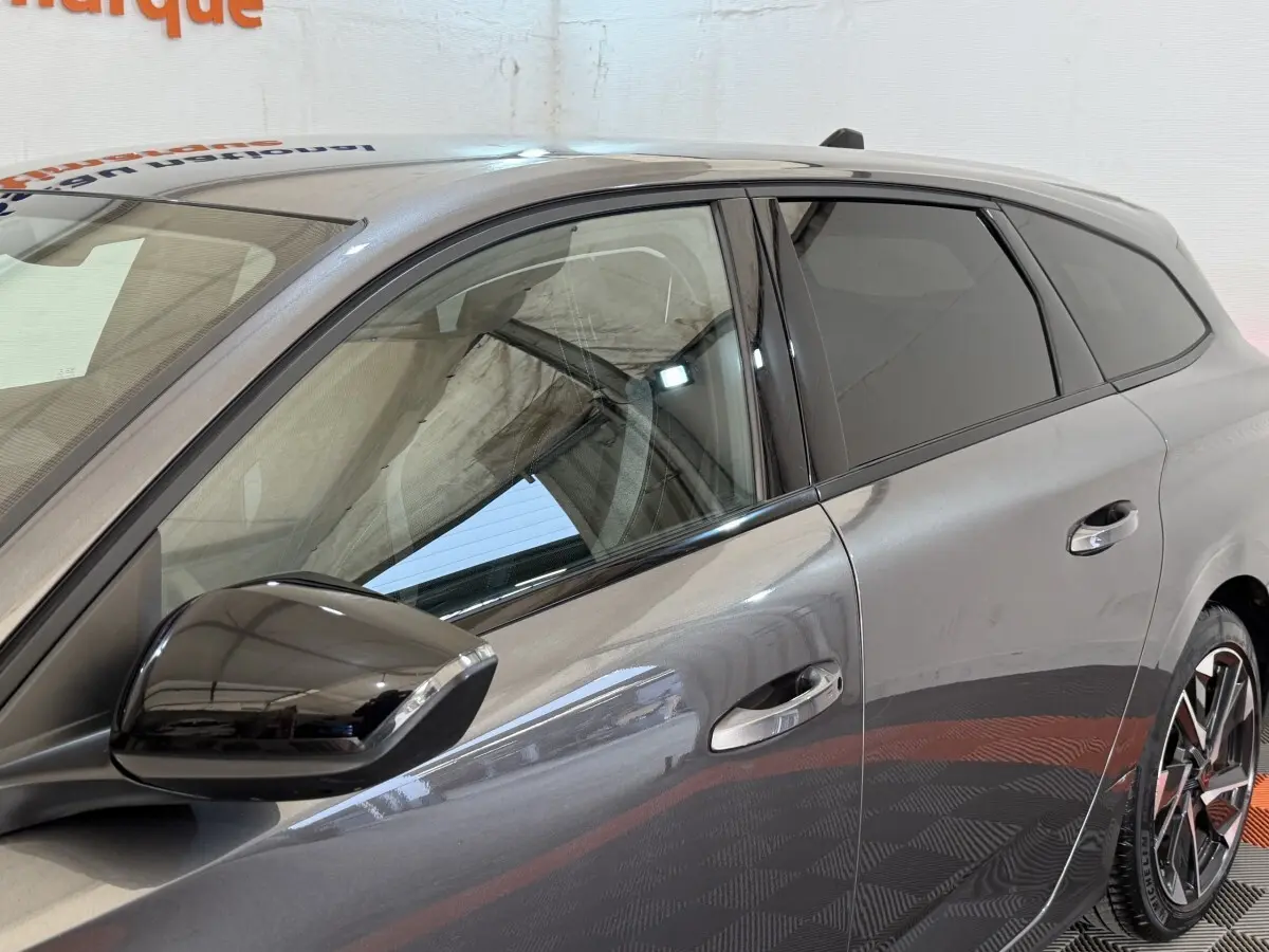 Vue côté gauche avant d'une Peugeot 308 SW gris foncé avec rétroviseur noir brillant et vitres teintées.