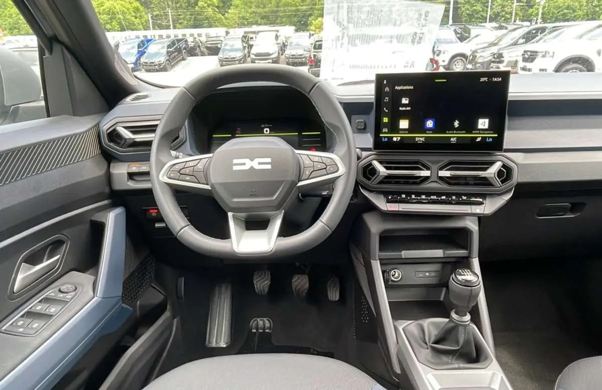 Vue intérieure frontale du tableau de bord du Dacia Bigster 2025, volant cuir et écran tactile central visible.