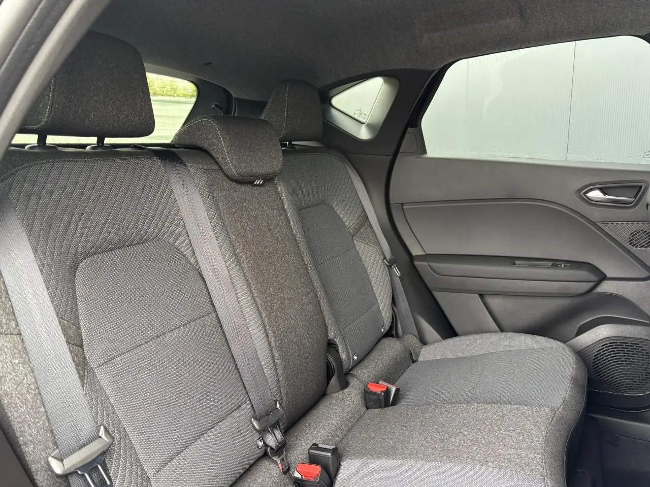 Vue intérieure sur la banquette arrière grise du Renault Captur 2025, avec ceintures et appuis-tête visibles côté droit.