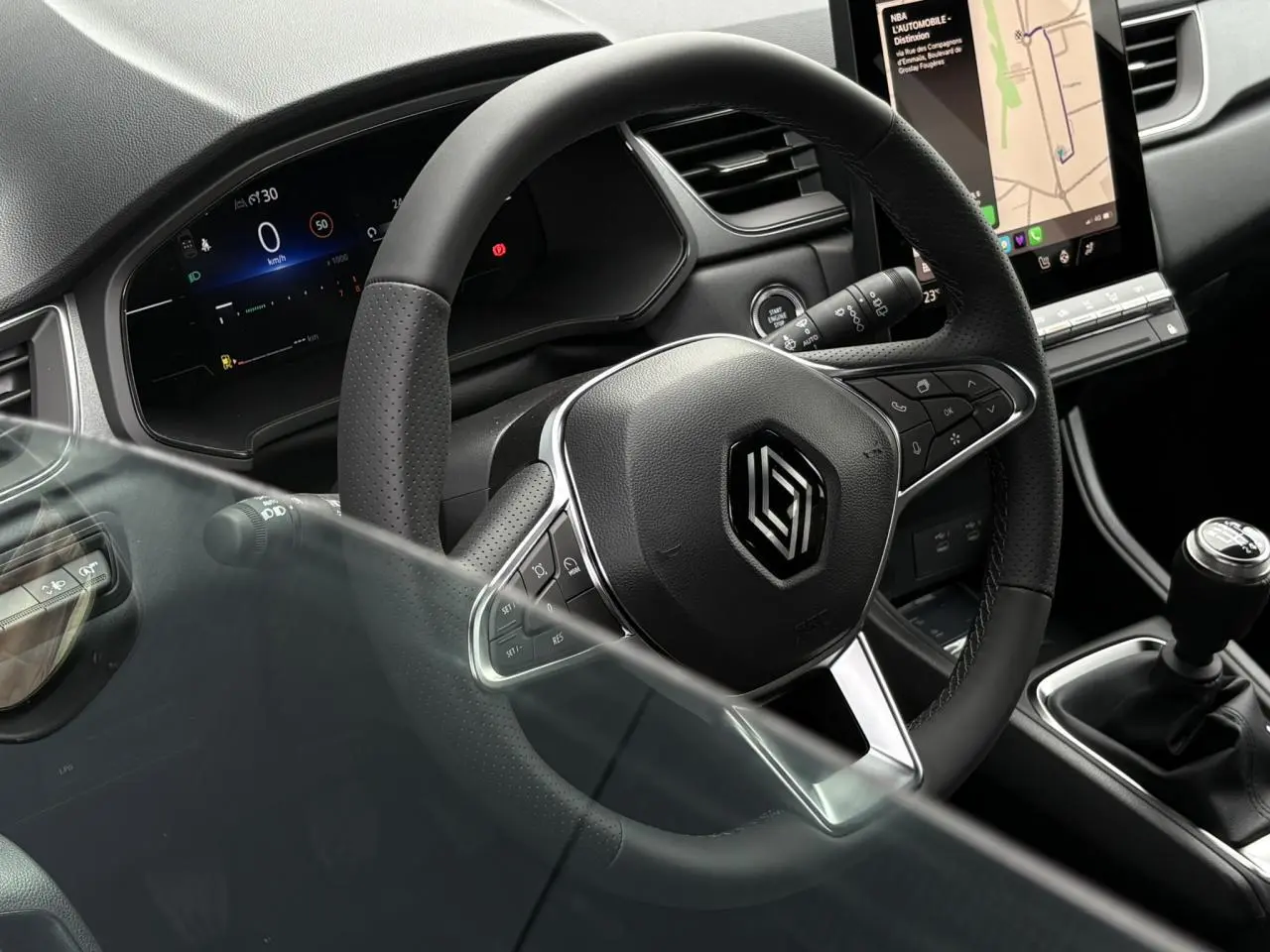 Vue rapprochée du volant noir et du levier de vitesses manuel du Renault Captur 2025 avec écran tactile vertical visible.