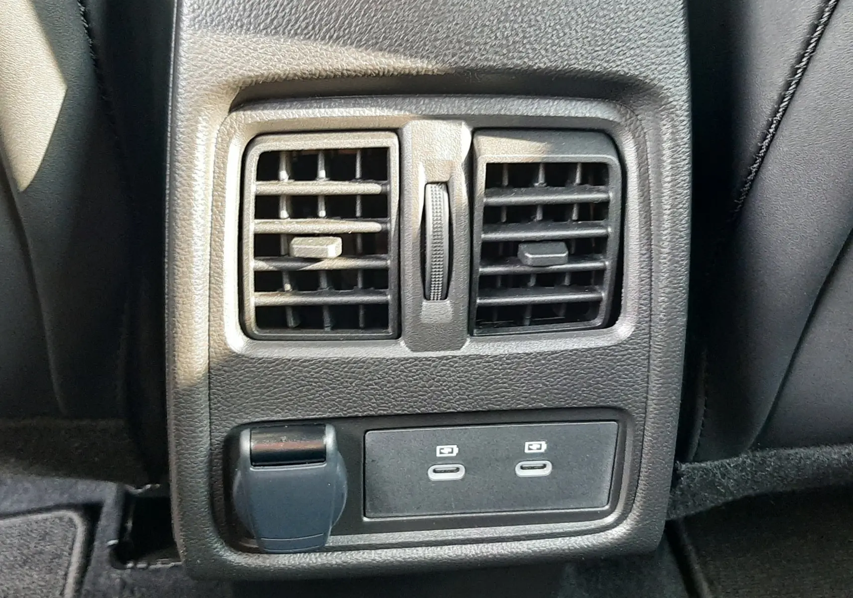 Gros plan sur la console arrière noire du Renault Captur 2024 avec deux aérateurs et ports USB-C visibles.