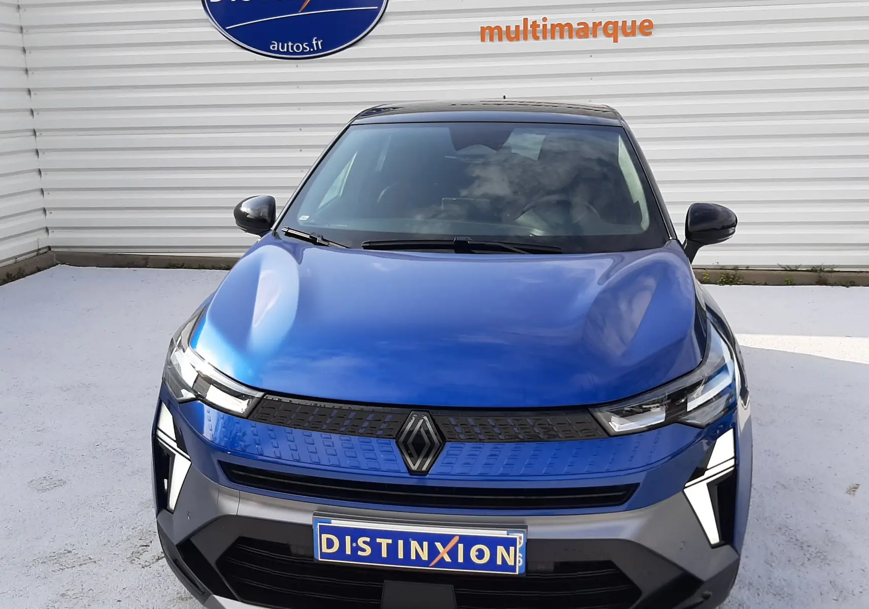 Vue frontale d'un Renault Captur 2024 bleu iron avec toit noir, mettant en valeur sa calandre moderne et ses phares LED distinctifs.