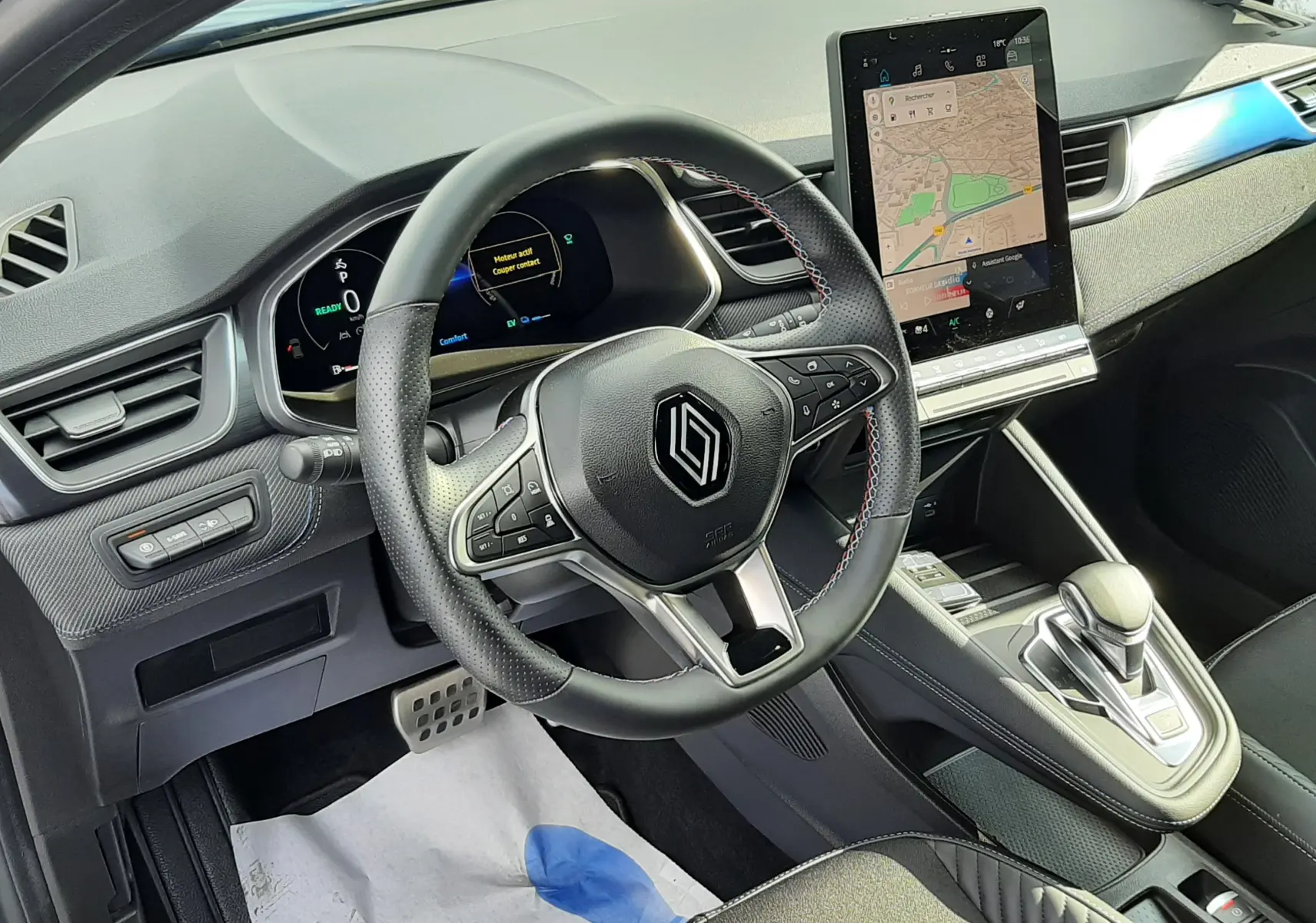 Intérieur avant du Renault Captur 2024, tableau de bord moderne avec écran tactile vertical et volant multifonction noir.