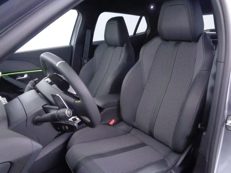 Vue intérieure côté conducteur du Peugeot 2008 gris Artense avec sièges sport en tissu tri-matières et surpiqûres vertes.