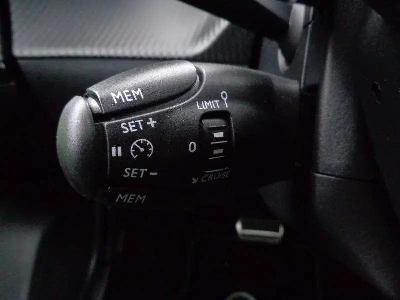 Gros plan sur la commande de régulateur de vitesse noire dans l'habitacle du Peugeot 2008 gris Artense 2023.