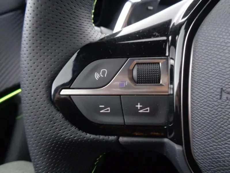 Gros plan sur les commandes du volant cuir perforé du Peugeot 2008 gris Artense avec touches de réglage du volume et appel.