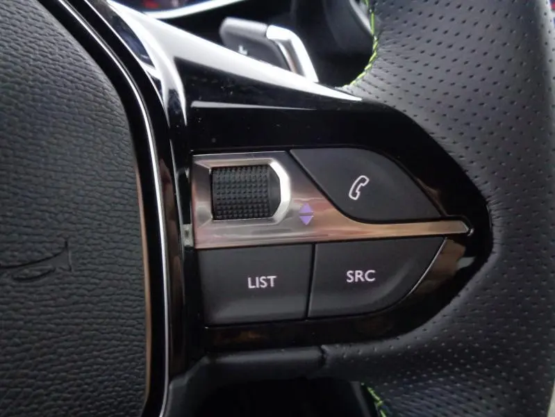 Gros plan sur les commandes gauche du volant cuir perforé du Peugeot 2008 gris Artense, avec molette et boutons d’appel.