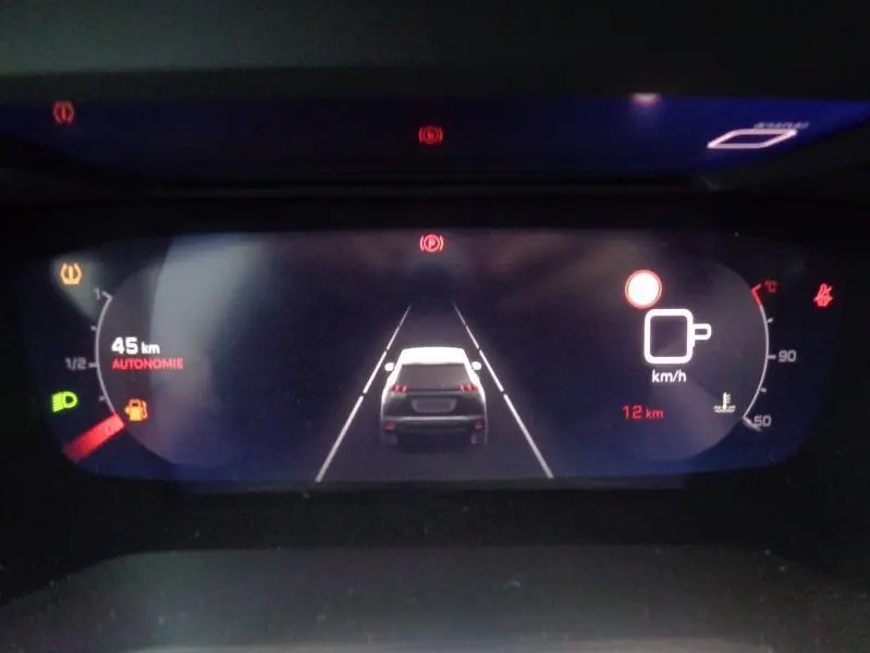 Affichage numérique du tableau de bord du Peugeot 2008 gris Artense montrant autonomie et vitesse, vue arrière stylisée du véhicule.