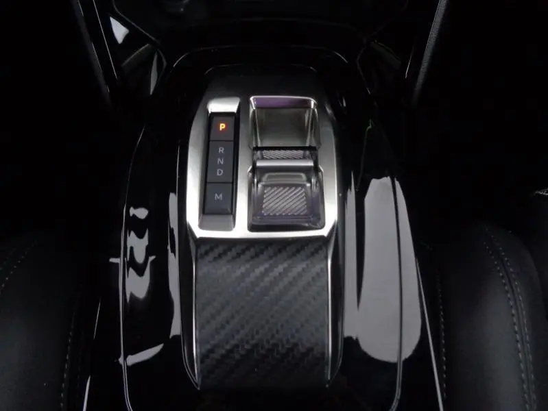 Gros plan sur la commande de boîte automatique noire avec insert carbone du Peugeot 2008 Gris Artense 2023.