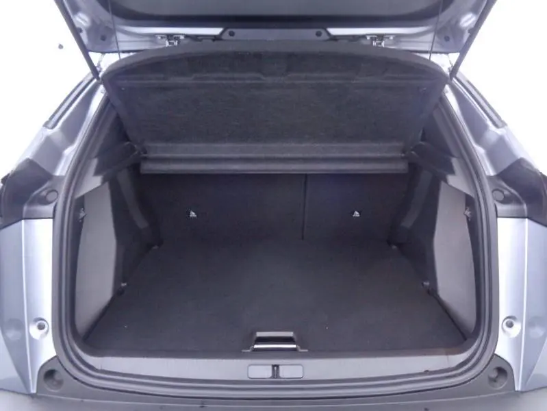 Coffre ouvert du Peugeot 2008 gris Artense, vue arrière montrant l'espace de chargement vide et la tablette cache-bagages relevée.