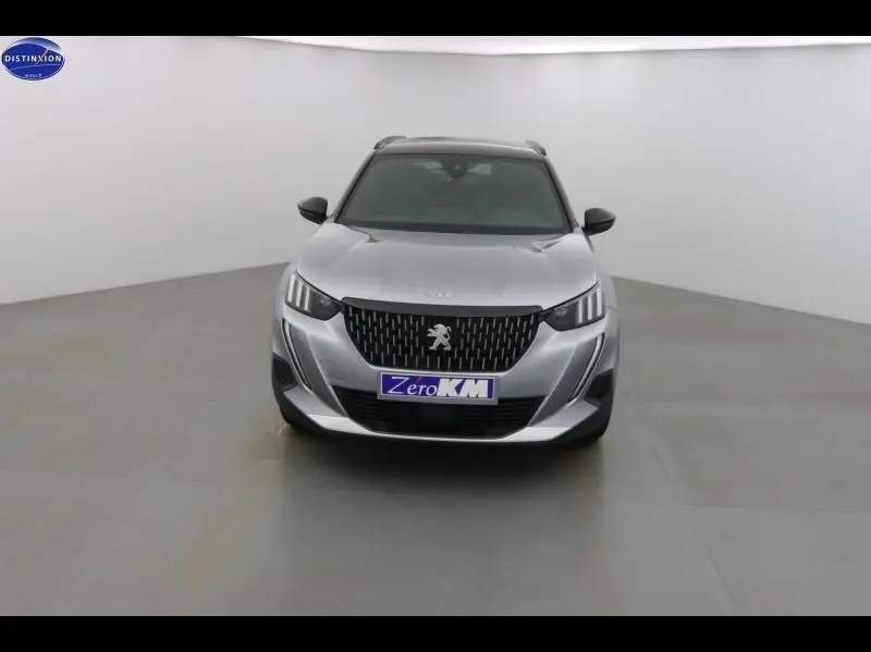 Vue frontale d'un Peugeot 2008 gris Artense avec calandre noire et logo lion central bien visible.