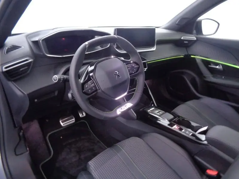 Intérieur avant droit du Peugeot 2008 gris Artense avec volant cuir compact et éclairage d'ambiance vert néon.