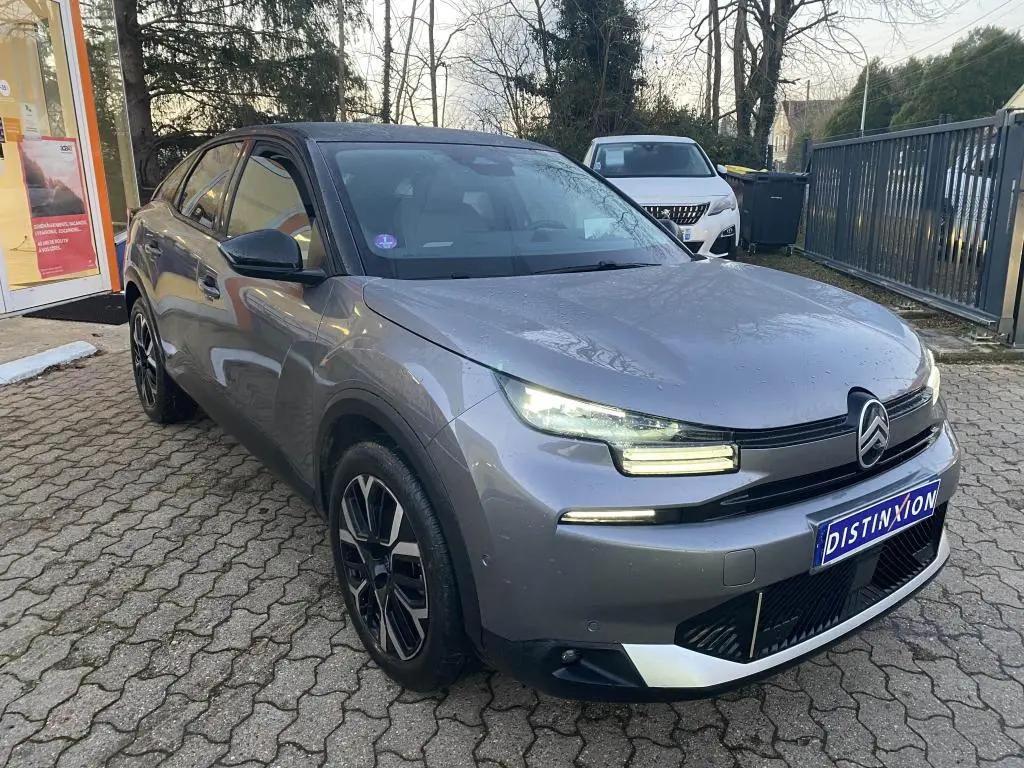 Citroën C4 gris foncé vue 3/4 avant droit avec toit noir et feux LED allumés sur parking extérieur.