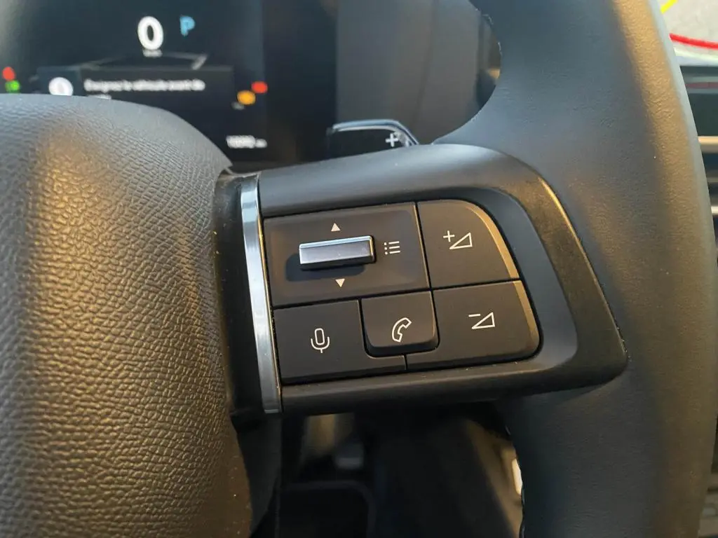 Gros plan sur les commandes multifonctions à gauche du volant de la Citroën C4 2025 gris foncé.