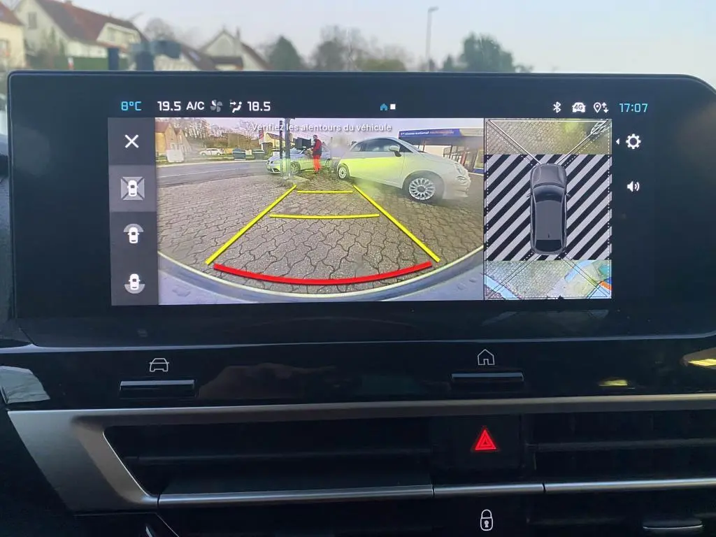 Écran de recul du Citroën C4 2025 gris foncé avec guidage jaune et rouge et vue 360° du stationnement.