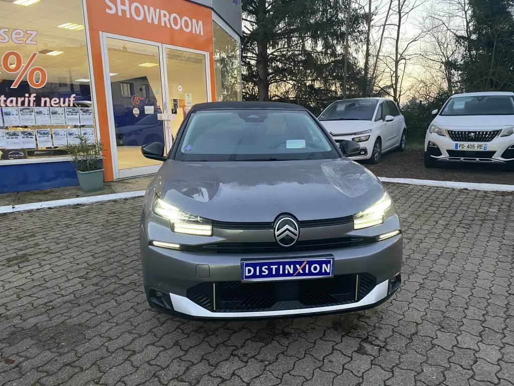 Citroën C4 gris foncé vue de face avec phares LED allumés et toit bi-ton noir devant un showroom.