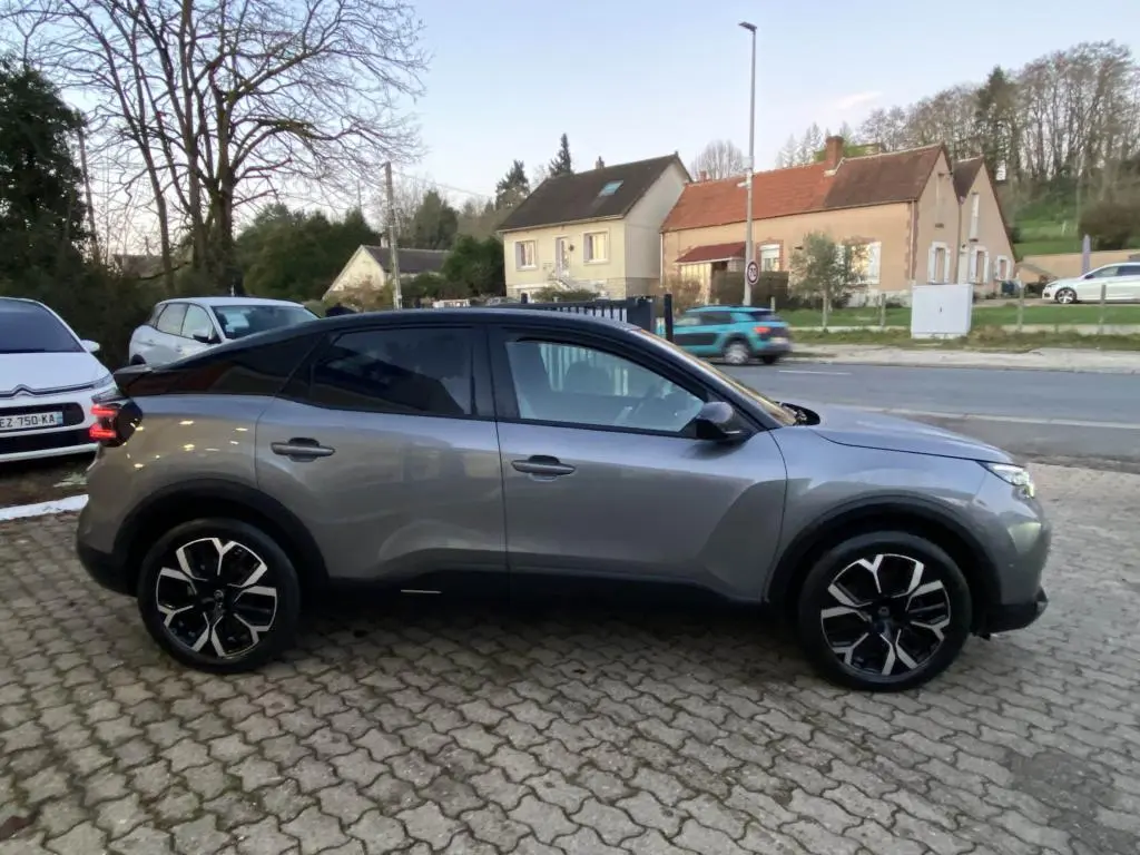 Vue latérale droite d'une Citroën C4 2025 gris foncé avec toit bi-ton noir et jantes alliage distinctives.