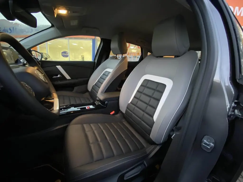 Vue intérieure côté gauche des sièges avant en cuir noir et gris clair de la Citroën C4 2025 gris foncé.