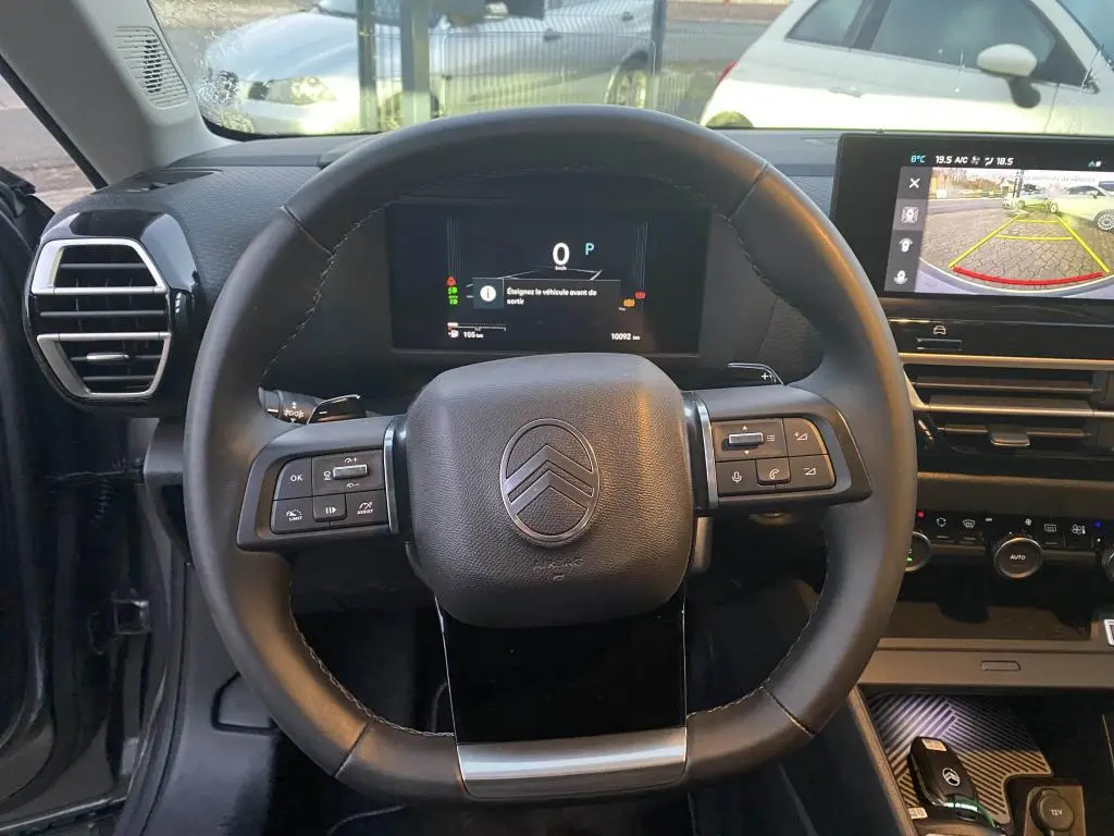 Vue frontale du volant et du tableau de bord numérique de la Citroën C4 2025, avec écran central affichant la caméra de recul.