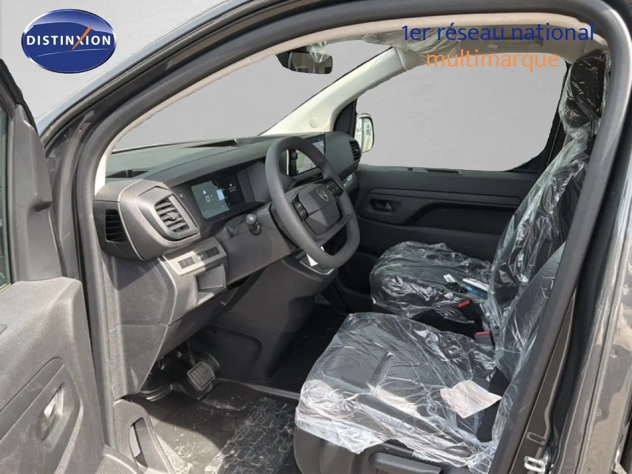 Intérieur avant du Citroën Jumpy gris titane, vue côté conducteur avec sièges protégés par film plastique.