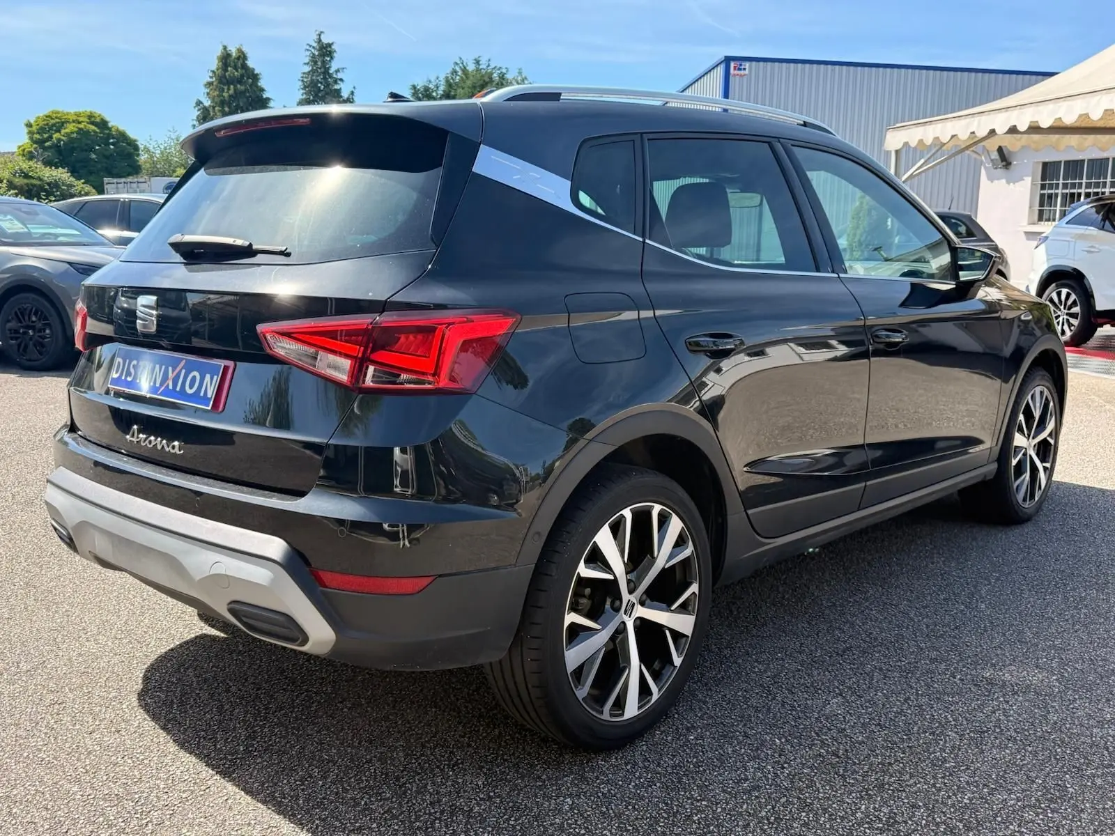 Vue 3/4 arrière droite d'une SEAT Arona noire avec jantes alliage et toit contrasté gris clair.