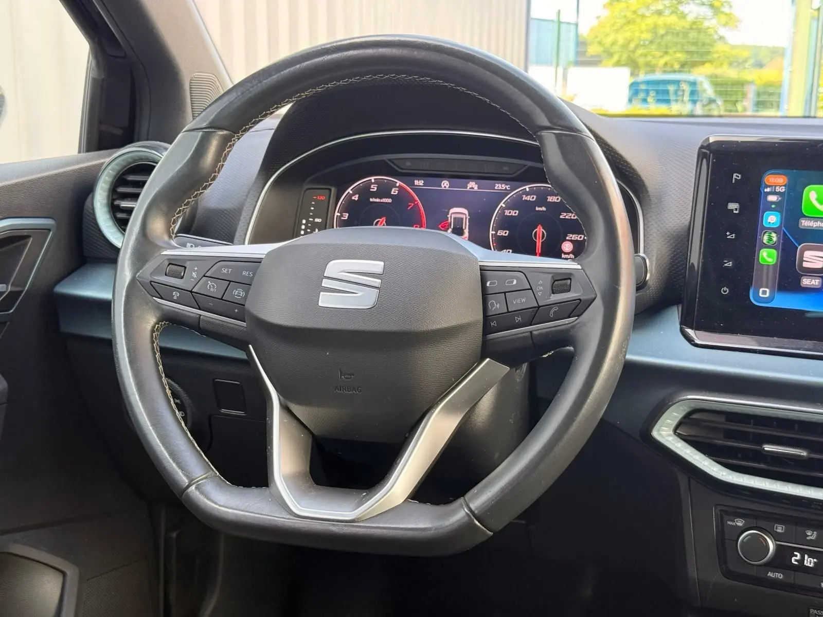 Vue rapprochée du volant en cuir noir avec logo SEAT, tableau de bord numérique et écran tactile central du SEAT Arona 2022.