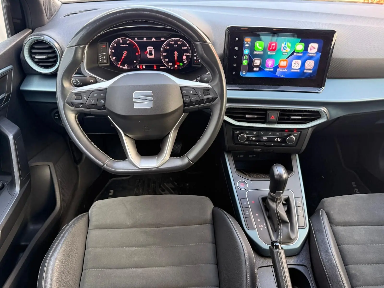 Vue intérieure du poste de conduite du SEAT Arona 2022, volant cuir noir, écran tactile central affichant Apple CarPlay.