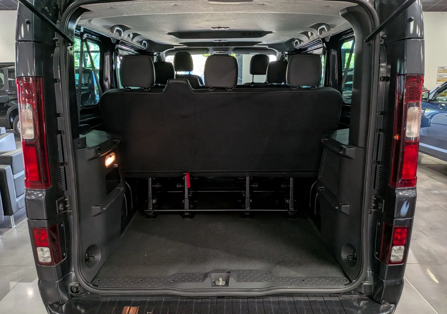 Vue arrière ouverte du Nissan Primastar Combi gris Comète 2025, montrant l'espace intérieur et les sièges arrière.