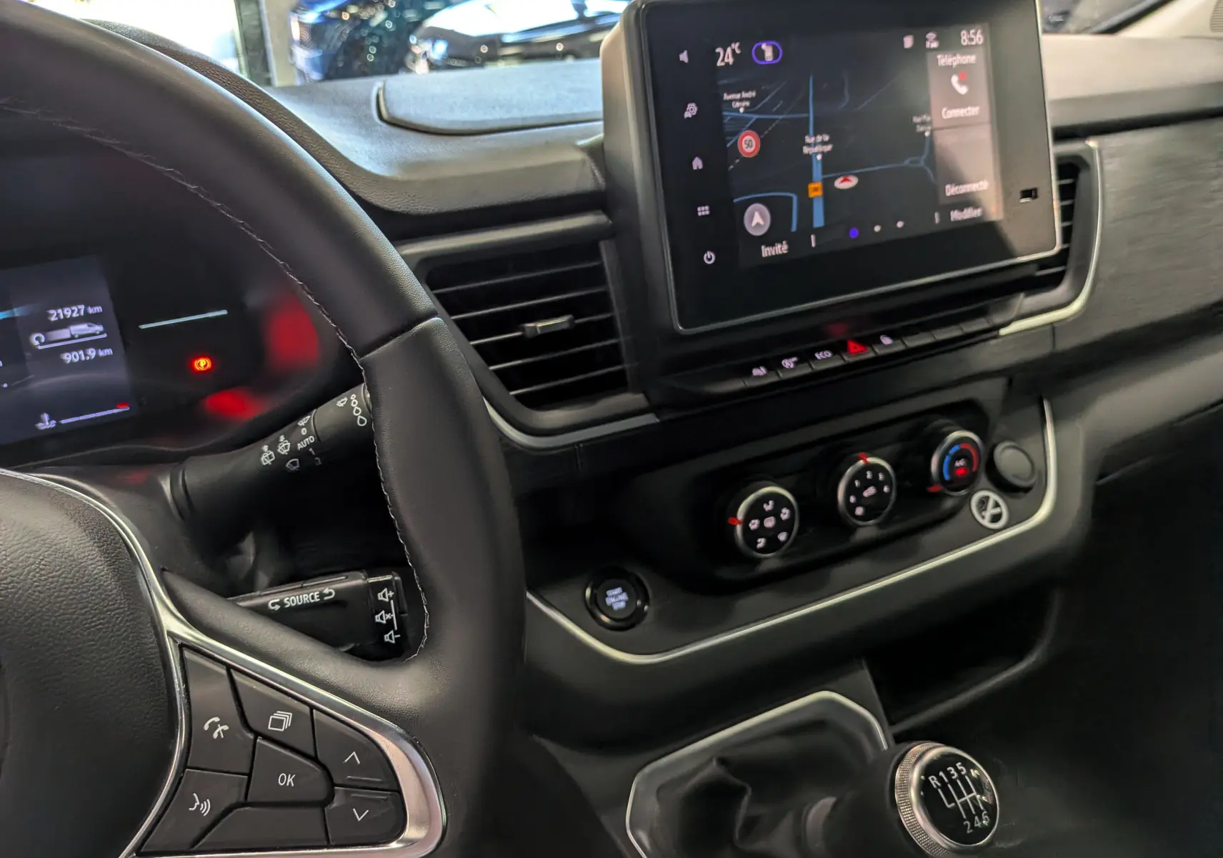 Vue intérieure côté conducteur du tableau de bord et console centrale du Nissan Primastar Combi gris avec boîte manuelle et écran tactile.