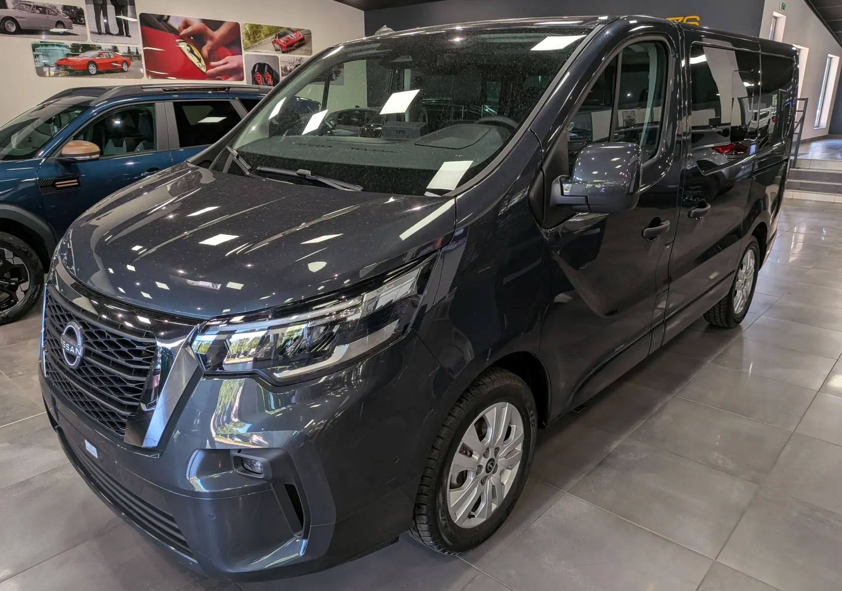 Nissan Primastar Combi gris Comète vue 3/4 avant droit, mettant en valeur sa calandre imposante et ses phares LED modernes.