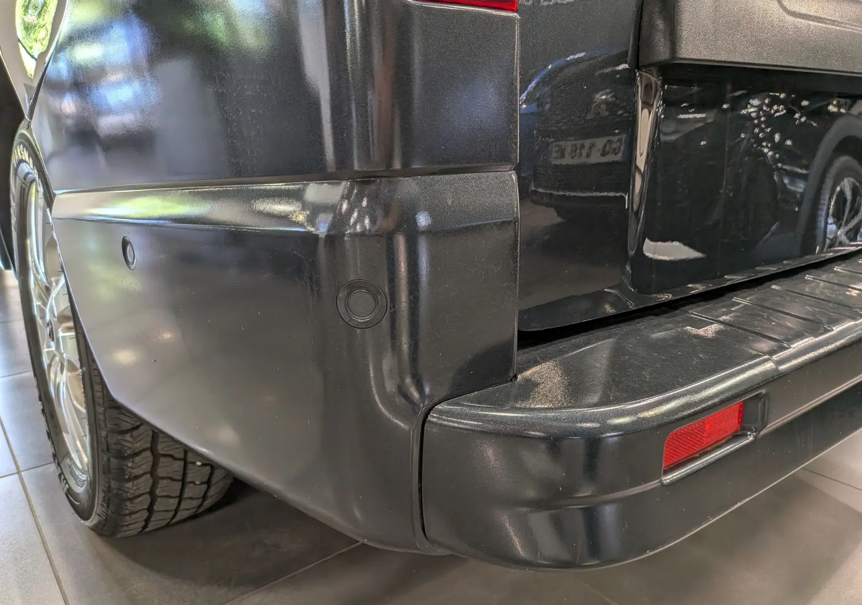 Gros plan sur l’angle arrière gauche du Nissan Primastar Combi gris Comète, mettant en valeur le pare-chocs et le feu arrière.