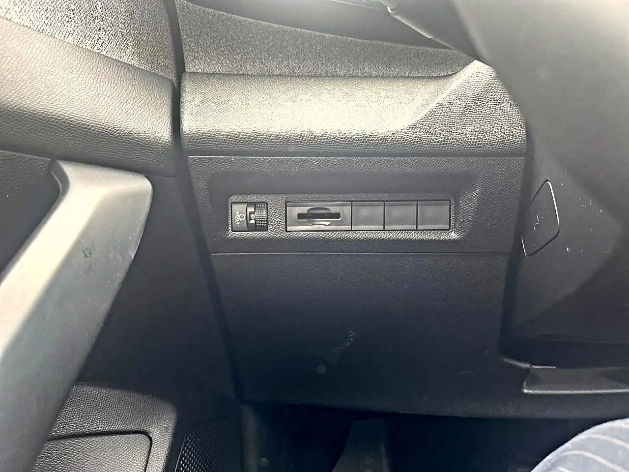 Détail de la console côté conducteur de la Peugeot 308 noire, montrant les commandes d'éclairage et les boutons vierges.