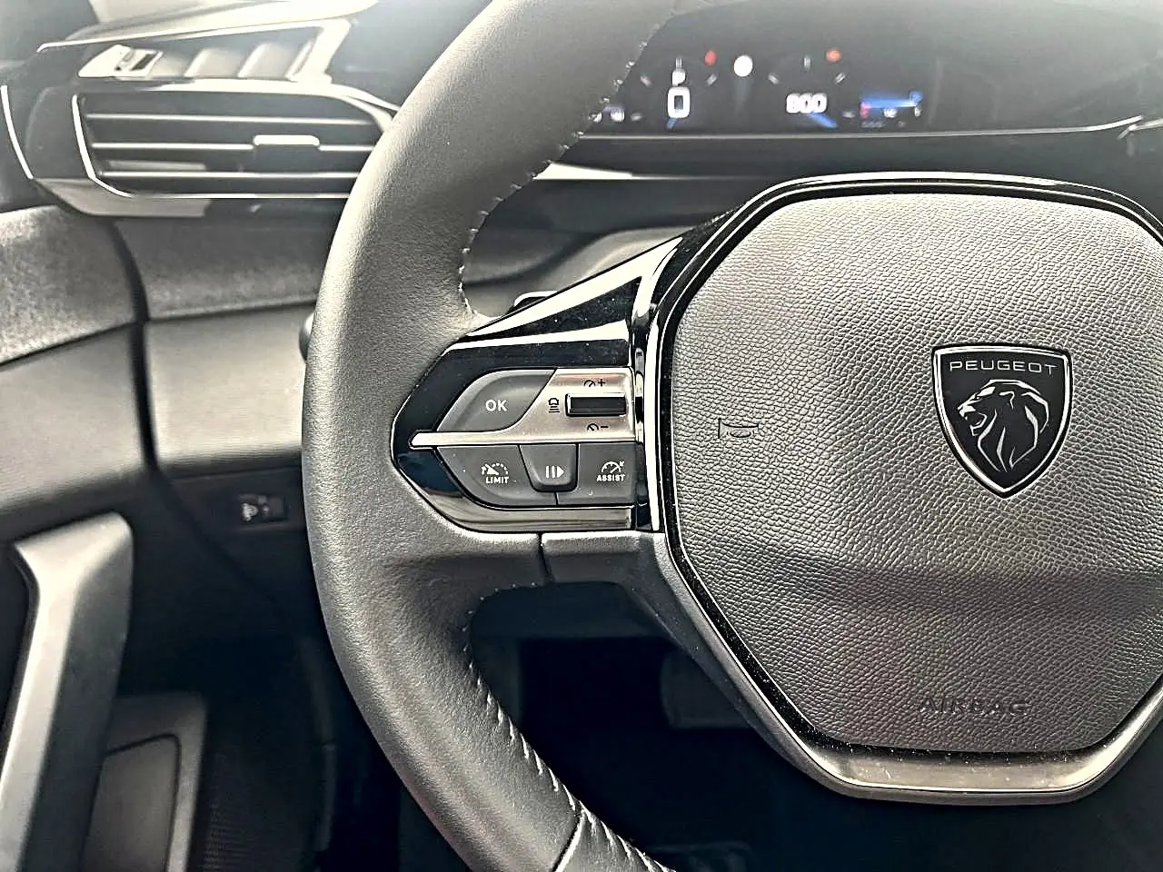 Vue rapprochée du volant noir de la Peugeot 308 2025 avec commandes multifonctions et logo lion central.