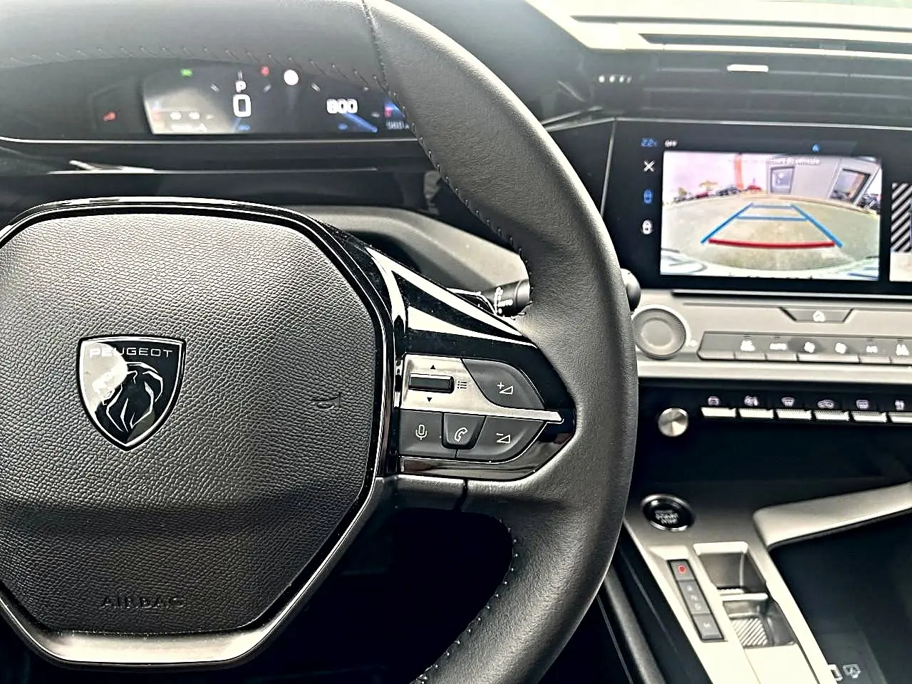 Vue rapprochée du volant noir Peugeot 308 2025 avec commandes multifonctions et écran tactile affichant la caméra de recul.