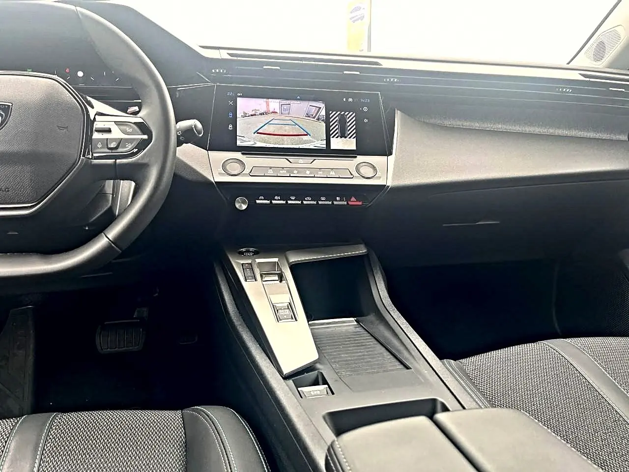 Vue intérieure avant de la Peugeot 308 noire, montrant le volant, écran tactile et console centrale moderne.