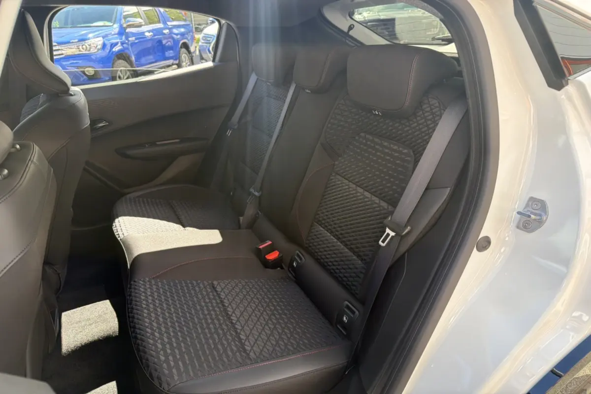 Vue intérieure côté droit sur la banquette arrière noire avec surpiqûres rouges d'une Renault Clio blanc glacier 2026.