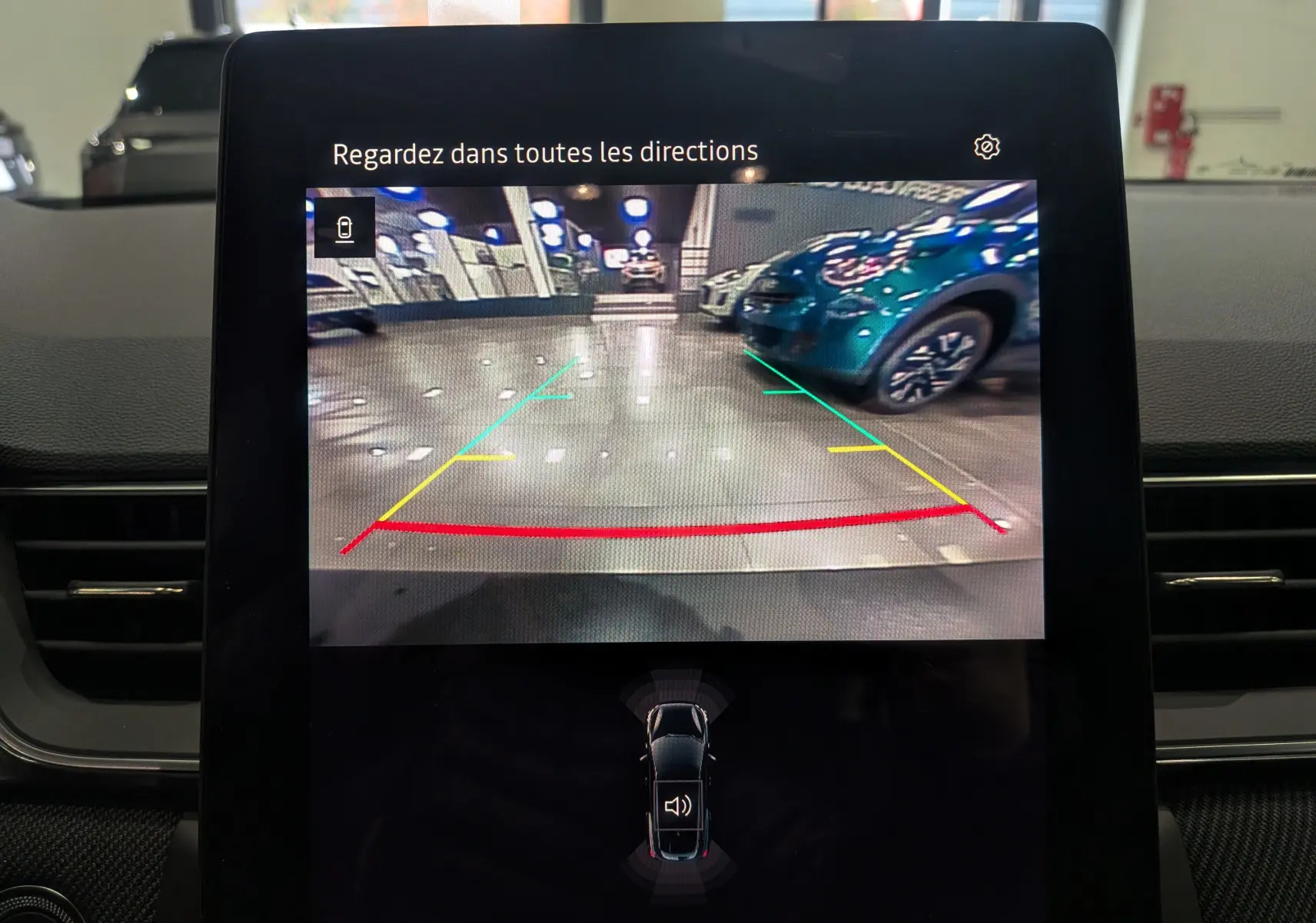 Écran de caméra de recul montrant un parking intérieur avec une Renault Symbioz gris Cassiopé en arrière-plan côté droit.