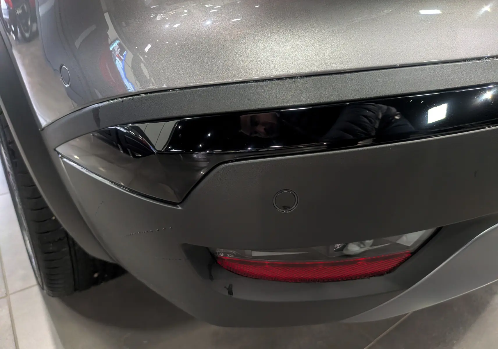 Gros plan sur le pare-chocs arrière gris Cassiopé du Renault Symbioz E-Tech, avec feu antibrouillard et capteur de recul.