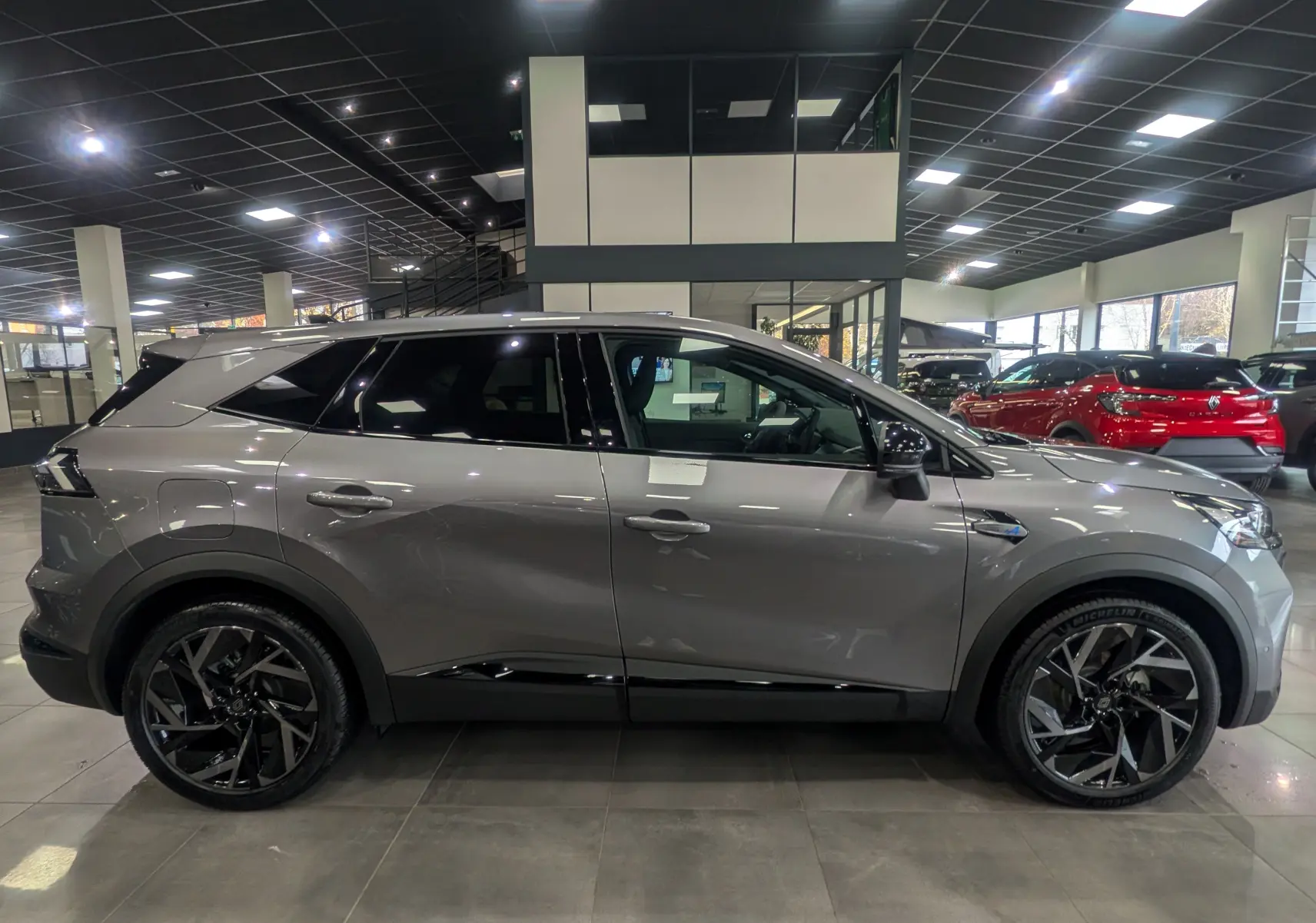 Profil côté gauche du Renault SYMBIOZ gris Cassiopé, version hybride Esprit Alpine, avec jantes noires distinctives en showroom.